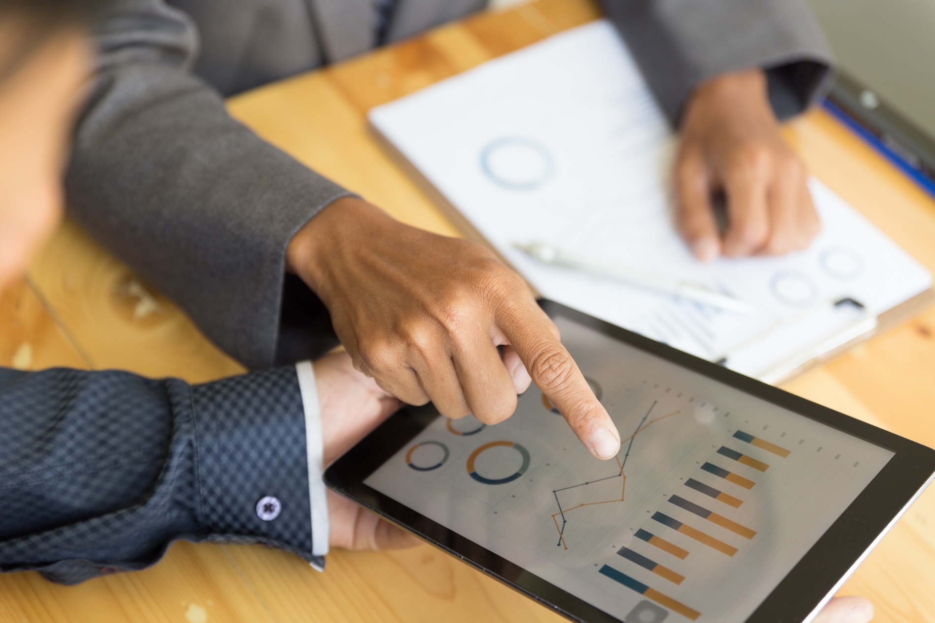 Business professionals analyzing financial data on a tablet during a business valuation meeting to assess a company’s readiness for sale.